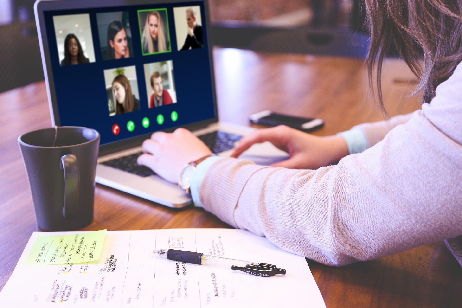 laptop with photos of individuals in a meeting